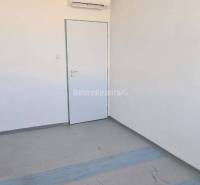 Kancelář s bílými stěnami a klimatizací, podlahou s dřevěným dekorem.