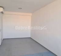 Světlé kancelářské prostory s bílými stěnami a oknem, podlaha s dřevěným dekorem.