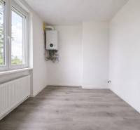 Pokoj s bílými stěnami a podlahou s dřevěným dekorem v 3-pokojovém bytě.