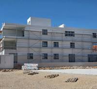 Budova ve městě SRIMA s lešením a nepořádkem na zemi.