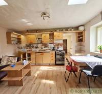 Kuchyně v rodinném domě s podlahou s dřevěným dekorem, světlý interiér a jednoduchý nábytek.