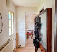 Interiér rodinného domu s úzkou chodbou a místností na konci.