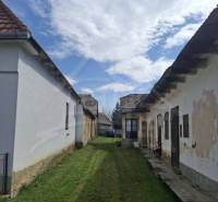 Starší rodinný dům se zahradou a oblačnou oblohou.