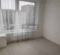 Světlý pokoj s velkými okny a podlahou s dřevěným dekorem v 2-pokojovém bytě.