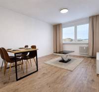 Jídelní stůl a konferenční stolek na podlaze s dřevěným dekorem v 2pokojovém bytě.