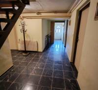 Interiér s černými obkladovými dlaždicemi a schodištěm v rodinném domě.