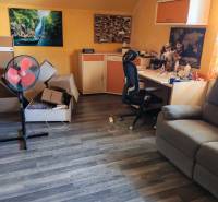 Pokoj v rodinném domě s pracovním stolem, židlí a podlahou s dřevěným dekorem.