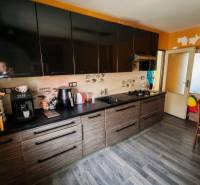 Kuchyně s černými skříňkami a podlahou s dřevěným dekorem v rodinném domě.