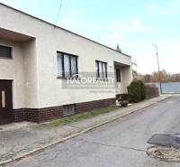 Rodinný dům ve městě Poltár s rovnou střechou a garáží u cesty.