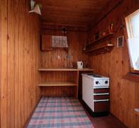 Dřevěné stěny, sporák a police v interiéru s podlahou s dřevěným dekorem.