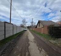 Venkovská cesta v Bohdanovicích, s pozemky pro bydlení na obou stranách ulice.