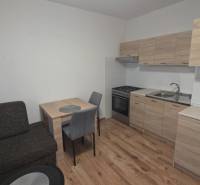 Kuchyně v 1-pokojovém bytě s dřevěným dekorem podlahy a nábytku.