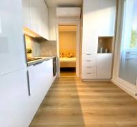 Světlá kuchyně v 2-pokojovém bytě s podlahou s dřevěným dekorem a bílými skříňkami.
