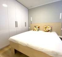 Ložnice s manželskou postelí, barevnými polštáři a skříní, 2pokojový byt.