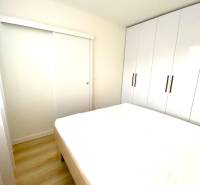 Ložnice v 2pokojovém bytě s postelí a velkou vestavěnou skříní.