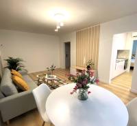 Jídelna v 2-pokojovém bytě s bílým stolem a podlahou s dřevěným dekorem.