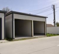 Garáže v Michali na Ostrově se dvěma otevřenými vjezdy, vedle cesty a plotu.