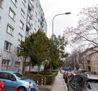 Vícepodlažní bytový dům na Ondavské ulici v Bratislavě - Nivy, obklopený auty a stromy.