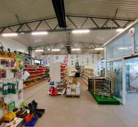 Obchodní prostory obsahující regály se zbožím, police a stojany s firemními reklamami.