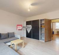 Obývací pokoj v rodinném domě s pohovkou, skříní a stolkem, podlaha s dřevěným dekorem.