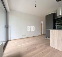 Světlý interiér 2pokojového bytu s velkými okny a dřevěnou podlahou.