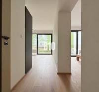 Světlý interiér dvoupokojového bytu s dřevěnou podlahou a velkými okny.