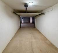 Uzavřený prostor garáže s betonovou podlahou a osvětlením.