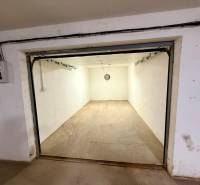 Prázdné garáže s betonovou podlahou a jednoduchým osvětlením.