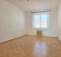 Prázdná místnost s oknem a podlahou s dřevěným dekorem v 3-pokojovém bytě.