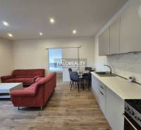 Obývací pokoj v 2-pokojovém bytě s pohovkou a podlahou s dřevěným dekorem.