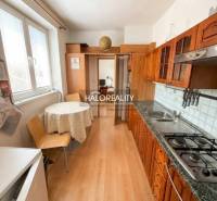 Kuchyně v 3-pokojovém bytě s podlahou s dřevěným dekorem a jídelním stolem.