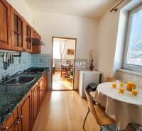 Kuchyně ve 3-pokojovém bytě s dřevěnými skříňkami a podlahou s dřevěným dekorem.