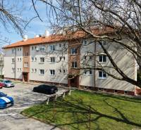 Bytový dům s parkovištěm a stromy na Vajanského ulici v Piešťanech.