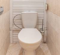 Toaleta s béžovými dlaždicemi v 3-pokojovém bytě, v čistém a jednoduchém designu.