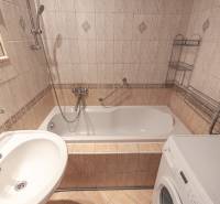 Koupelna v 3-pokojovém bytě s obklady, vanou a pračkou.