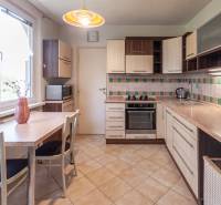 Kuchyně s mozaikovým obkladem a stolem v 3-pokojovém bytě je vybavena spotřebiči.