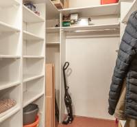 Šatník ve 3-pokojovém bytě s policemi a místem na zavěšení oděvů.