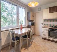 Kuchyně ve 3-pokojovém bytě s kachličkovanou stěnou a podlahou s dřevěným dekorem.