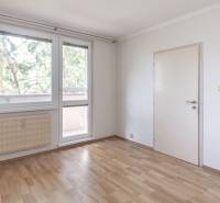 Pokoj ve 3-pokojovém bytě s podlahou s dřevěným dekorem a velkými okny.