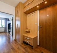Interiér 3-pokojového bytu s chodbou, dřevěnými skříňkami a podlahou s dřevěným dekorem.