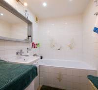 Koupelna ve 3-pokojovém bytě s vanou, umyvadlem a bílými dlaždicemi.