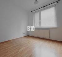 Prázdný pokoj se stěnami v 3-pokojovém bytě, podlaha s dřevěným dekorem, velké okno.