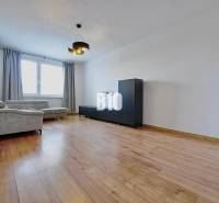 Obývací pokoj ve 3-pokojovém bytě s pohodlnou sedačkou a podlahou s dřevěným dekorem.