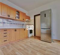 Kuchyně s dřevěnými skříňkami a podlahou s dřevěným dekorem v 3-pokojovém bytě.