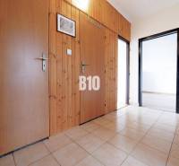 Chodba v 3-pokojovém bytě s dlažbou, dřevěným obložením a vstupy do dalších místností.