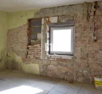 Pokoj v rodinném domě s cihlovými stěnami a kbelíkem na podlaze.