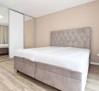 Ložnice v 3-pokojovém bytě s pohodlnou postelí, vestavěnou skříní a podlahou s dřevěným dekorem.