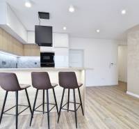 Kuchyně s barovým pultem a podlahou s dřevěným dekorem ve 3pokojovém bytě.