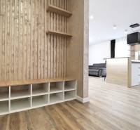 Interiér 3-pokojového bytu s podlahou s dřevěným dekorem, kuchyní a obývací částí.