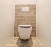 Toaleta s dřevěným dekorem a bílými obklady v 3-pokojovém bytě.